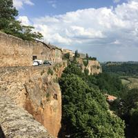The town wall on the rim, tufa falling away to the plain below.